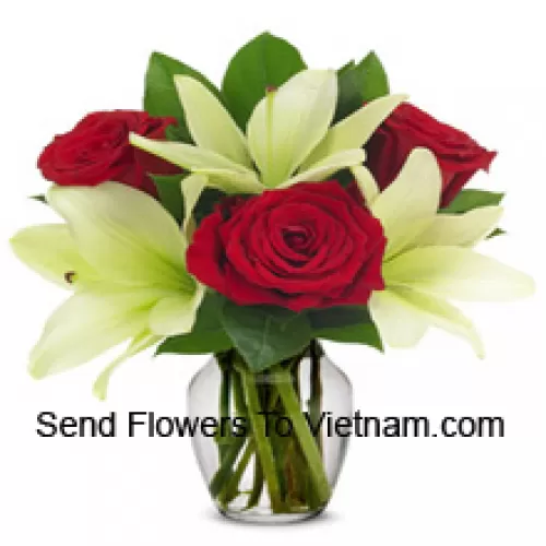 Rote Rosen und weiße Lilien mit saisonalen Füllstoffen in einer Glasvase